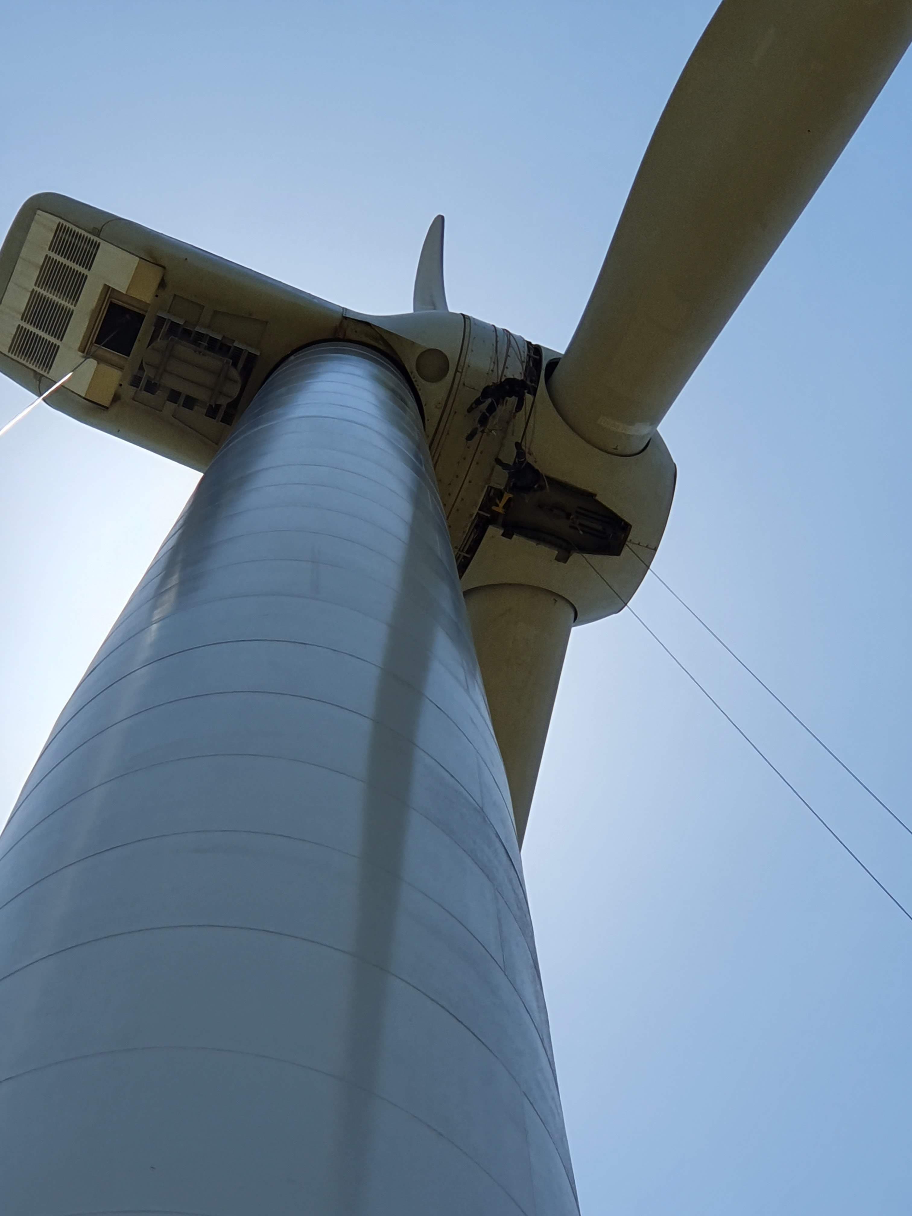 Alpinista industrial altamente capacitado suspenso na lateral de um aerogerador gigante
