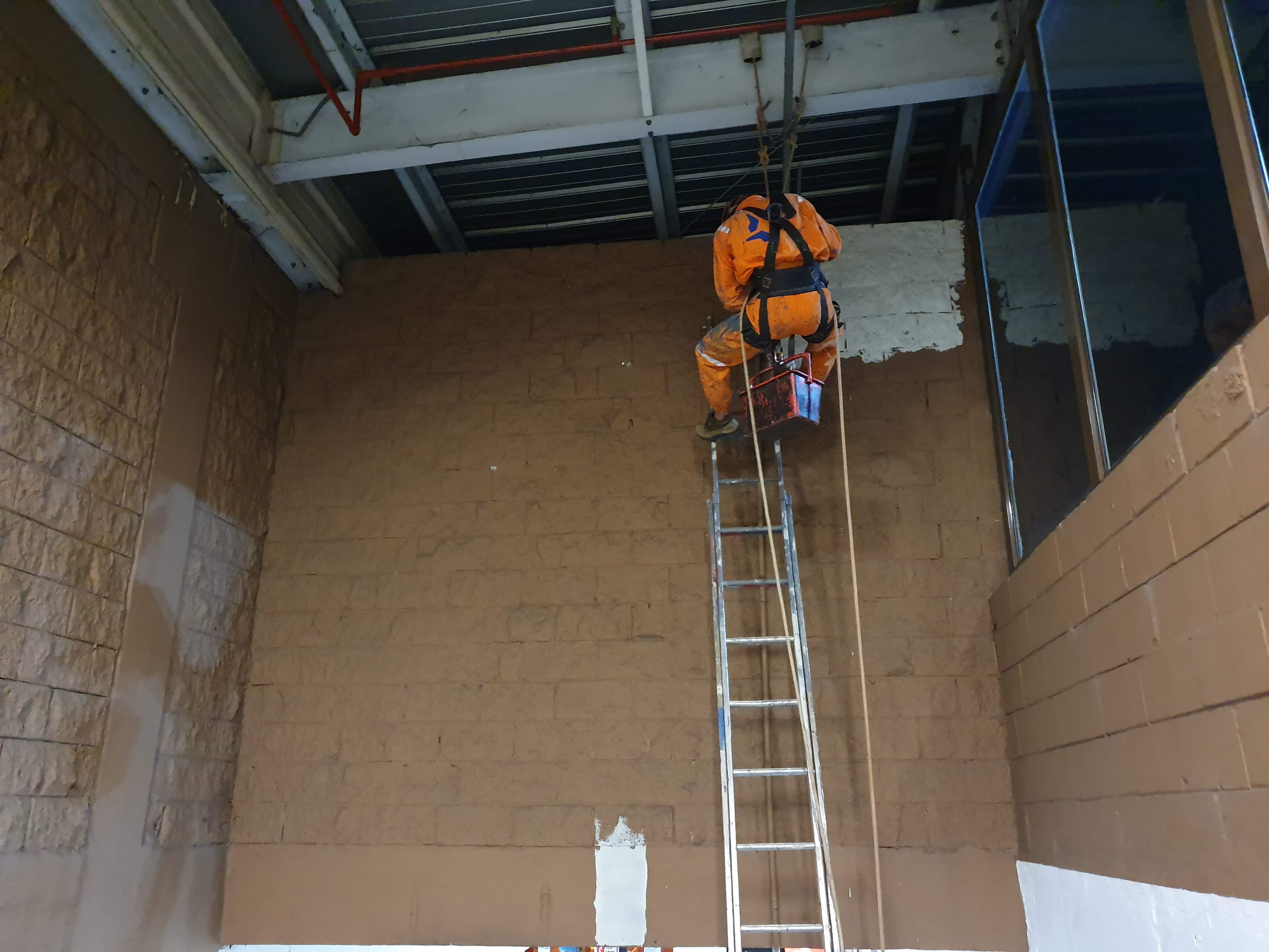 Operário alpinista da Pentágono realizando pintura de alta precisão em fachada corporativa